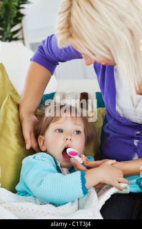 Sick little girl getting syrup from her caring mother