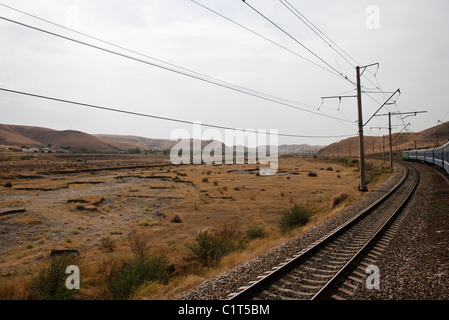 Uzbekistan, Bukhara, Railway and power lines running through barren landscape Stock Photo