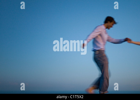 Couple walking together along edge of infinity pool, holding hands Stock Photo