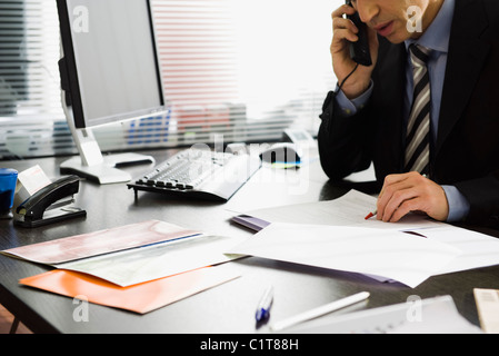 Executive talking on phone at desk Stock Photo