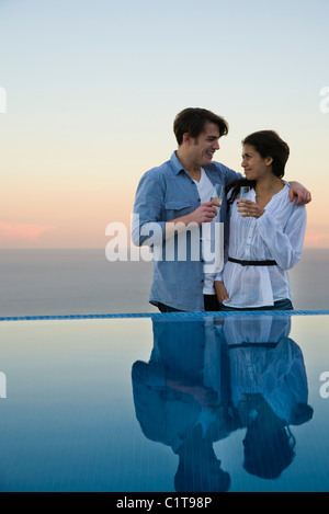 Couple standing at edge of infinity pool, enjoying champagne Stock Photo