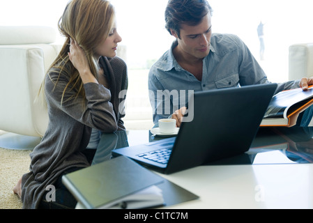 Couple sitting together at coffee table, looking at book Stock Photo