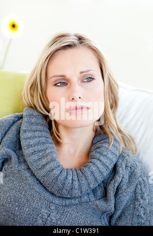 Tired woman lying on the sofa with a grey pullover Stock Photo
