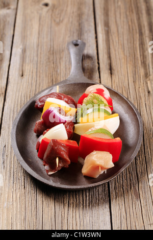 Raw Shish kebabs on a cast iron skillet Stock Photo