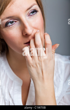 Sad, depressed caucasian blond young adult woman on neutral gray background Stock Photo