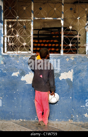 Young Talibé (students from a koranic school) beg  in front of a bakery on the streets of Saint Louis, Senegal Stock Photo