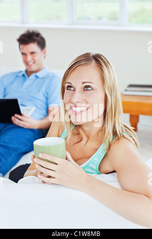 Young couple. woman drinking tea when man using a laptop Stock Photo