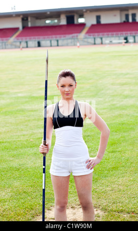 Confident athletic woman ready to throw a javelin standing in a stadium Stock Photo