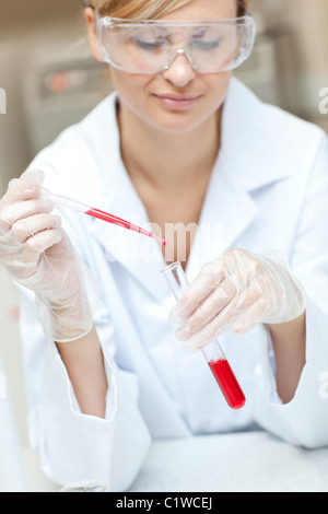 Close-up of a concentrated female scientist putting liquid in a test tube with a pipette Stock Photo