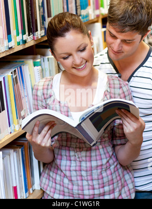 Two students enjoying reading a book together in the library Stock Photo