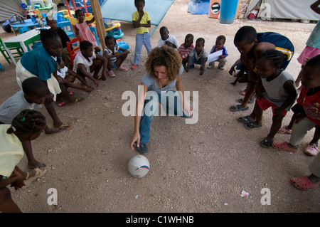 Noa Yaakov Israeli volunteer of Natan International Humanitarian Aid playing with young orphans in a makeshift camp for survivors of a 7.0 magnitude earthquake which struck Haiti on 12 January 2010 in  the outskirts of Port-au-Prince Stock Photo