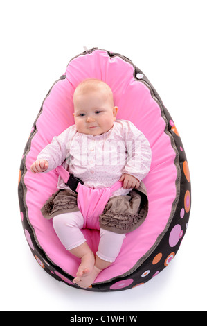 happy baby lying on an egg shaped cushion. isolated on white background Stock Photo