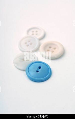 One blue button amongst various white buttons on a white background. Stock Photo