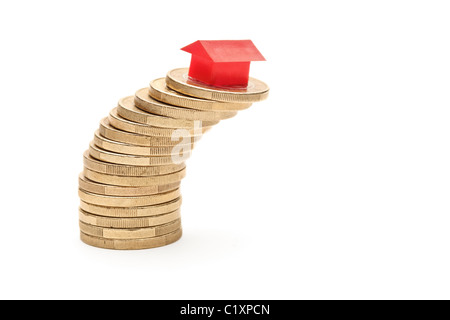 Small model house stacked on top of a pile of coins Stock Photo