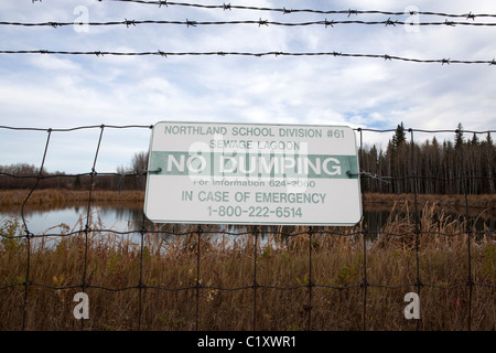 Warning sign on wire fence in front of sewage lagoon, Peace River, Alberta, Canada Stock Photo