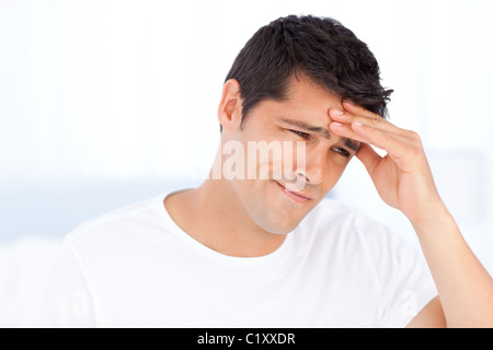Worried man having a headache sitting in his bedroom Stock Photo