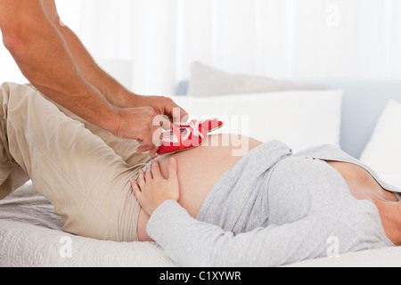 Affectionate man putting baby shoes on his wife Stock Photo