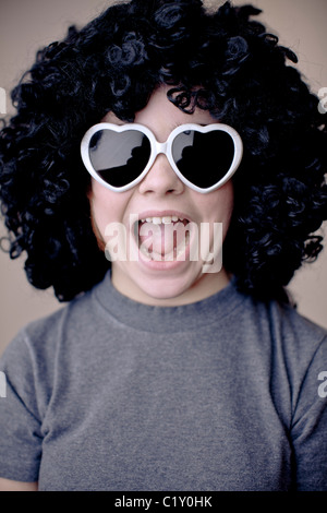 A teenage girl wearing funky white love heart glasses and a black afro wig Stock Photo