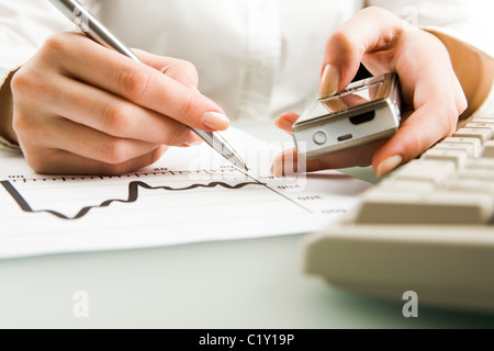 Close-up of female hands holding phone and pen Stock Photo