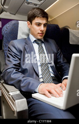 Image of busy male typing on laptop during flight Stock Photo