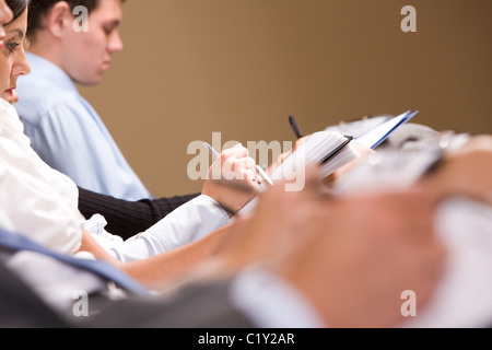 Close-up of female making notes or writing business plan at conference Stock Photo