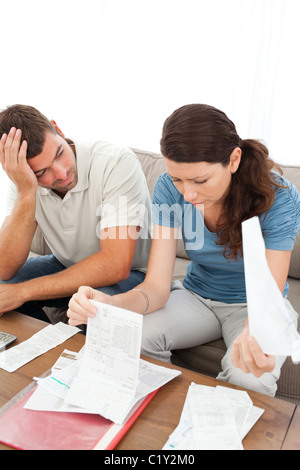 Stressed man and woman looking at bills in the living room Stock Photo