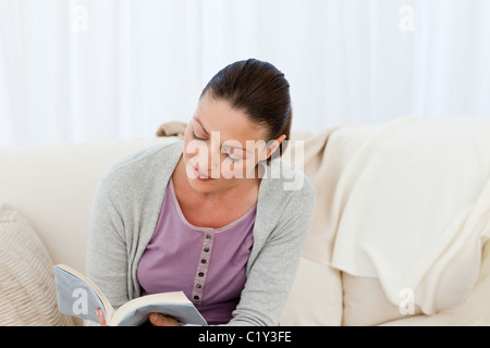 Passionate woman reading a fiction sitting on the sofa Stock Photo