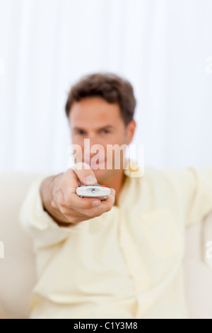 Close up of a man holding a remote on the sofa Stock Photo
