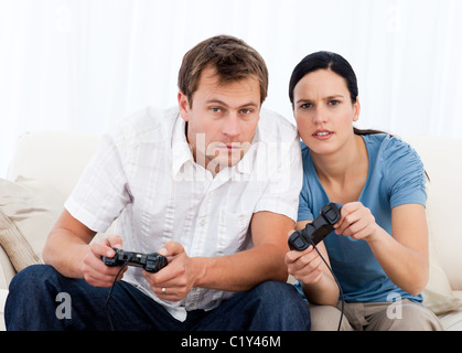 Concentrated couple playing video games together on the sofa Stock Photo
