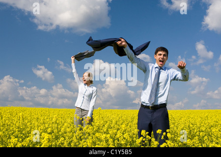 Portrait of happy business partners enjoying life and freedom in yellow field Stock Photo