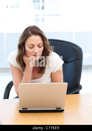 Thoughtful businesswoman working on laptop at a table Stock Photo