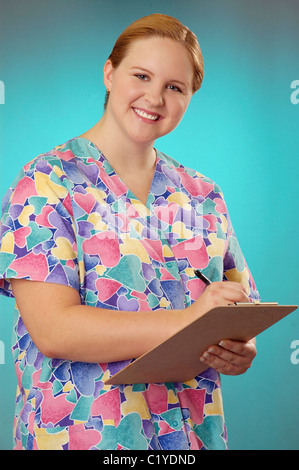 An attractive female medical professional with clipboard, smiling and making eye contact. Stock Photo