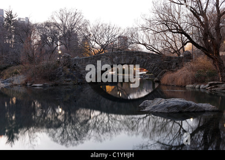 Gapstow Bridge as seen from the Pond with reflections in the water in New York's Central Park in Winter Stock Photo