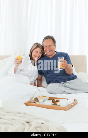 Lovely couple having breakfast in their bed Stock Photo