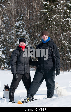 young couple hiking with snowshoes and puppies Stock Photo