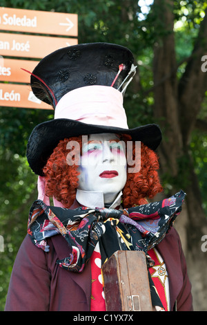 impassive mad hatter mime in Victorian costume with red wig & luridly painted whiteface makeup stands in Oaxaca Zocalo Mexico Stock Photo
