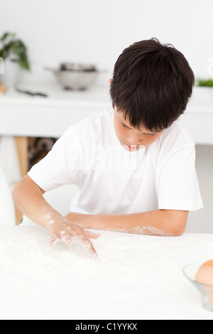 Cute boy playing with floor while cooking alone Stock Photo