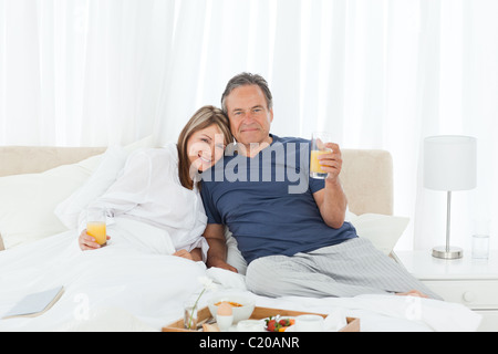 Lovely couple having breakfast in their bed Stock Photo