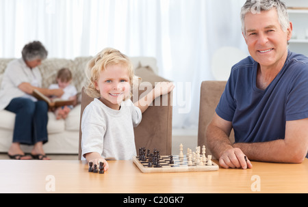 Young boy playing chess with his grandfather Stock Photo
