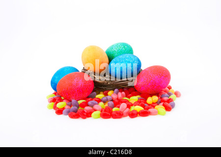 Mottled, colored Easter eggs in a natural twig nest sit on colorful jelly beans. Stock Photo