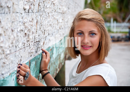 Young Scandinavian blond girl posing beside an old fishing boat in dry dock encrusted in barnacles.  Short depth of field. Stock Photo