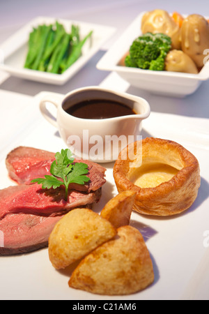 Traditional rare roast beef sunday dinner with vegtables and gravy. Stock Photo