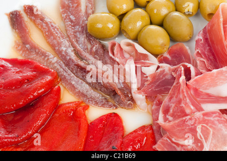 Spanish tapas with serrano ham, roasted piquillo peppers, olives anchovies and lettuce. Stock Photo