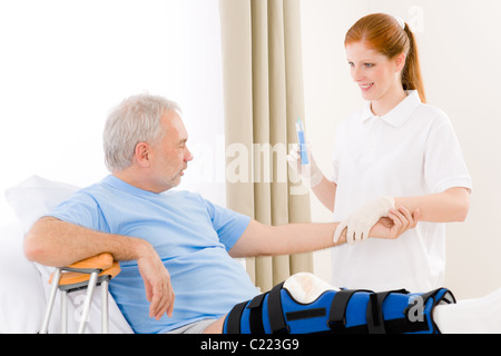 Hospital - female nurse give injection patient with broken leg Stock Photo