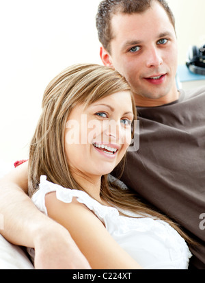 Portrait of a hugging couple sitting on a sofa Stock Photo