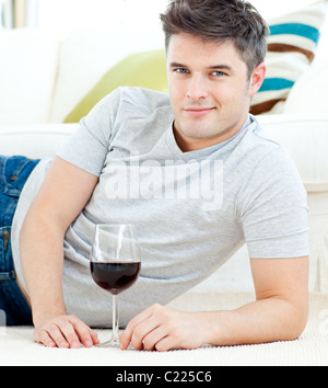 Handsome young man with wineglass lying on the floor Stock Photo