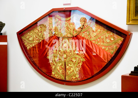 Red and gold Matador 's Cape; an exhibit on the wall in the museum tour of Sevilla bullring / bull ring building. Seville, Spain Stock Photo