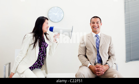 Furious businesswoman yelling through a megaphone at a colleague Stock Photo