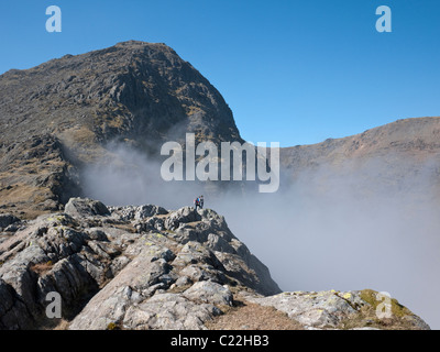 Walkers admire a cloud inversion in Cwm Dyli, from Bwlch y Saethau. Yr Wyddfa, the summit of Snowdon towers above. Stock Photo