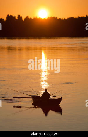 Fisherman trolling from a rowboat / skiff / dinghy at sunset at river Oulujoki Finland Stock Photo